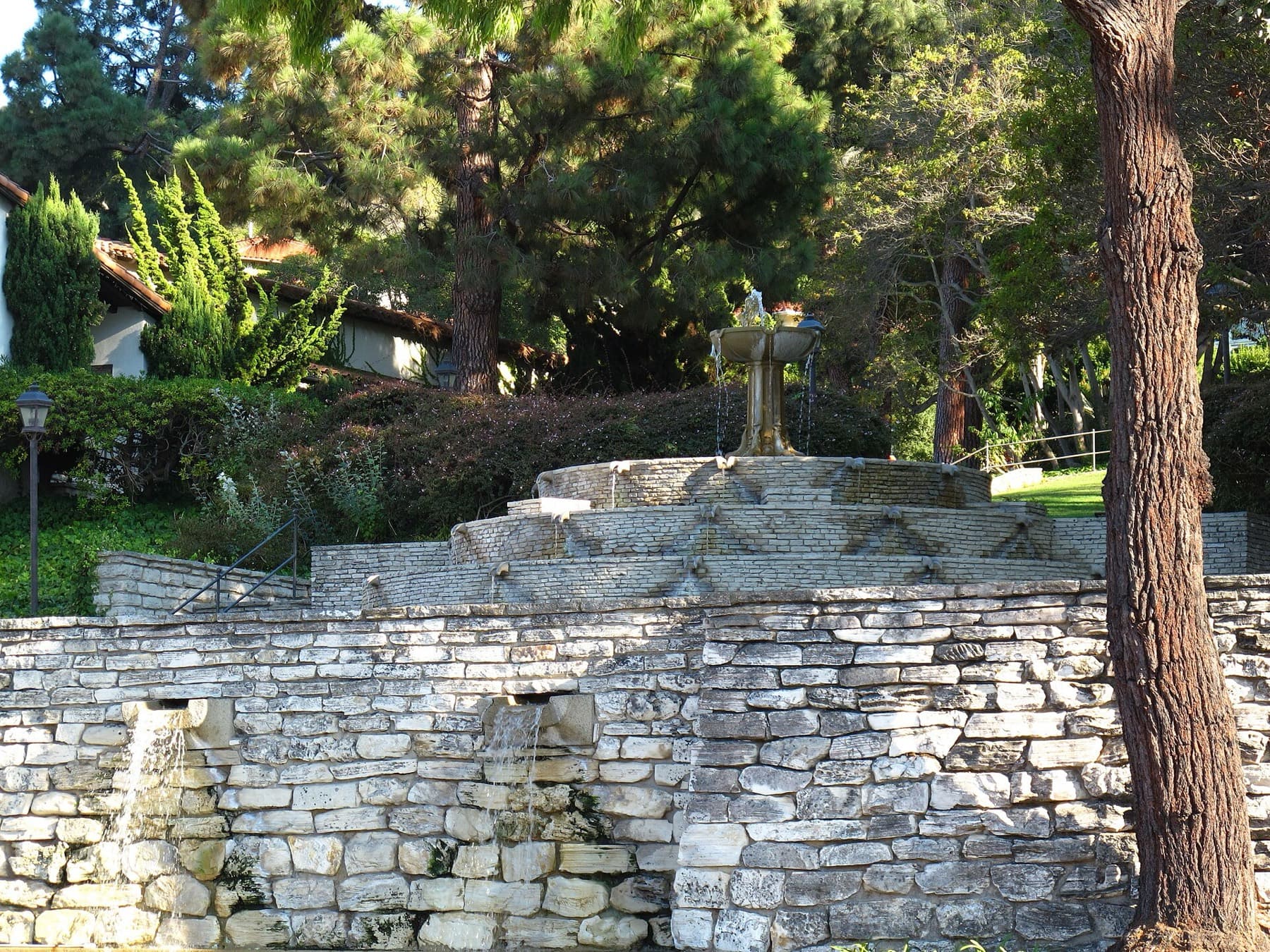 The Malaga Cove library's stone terraced fountain framed by pines