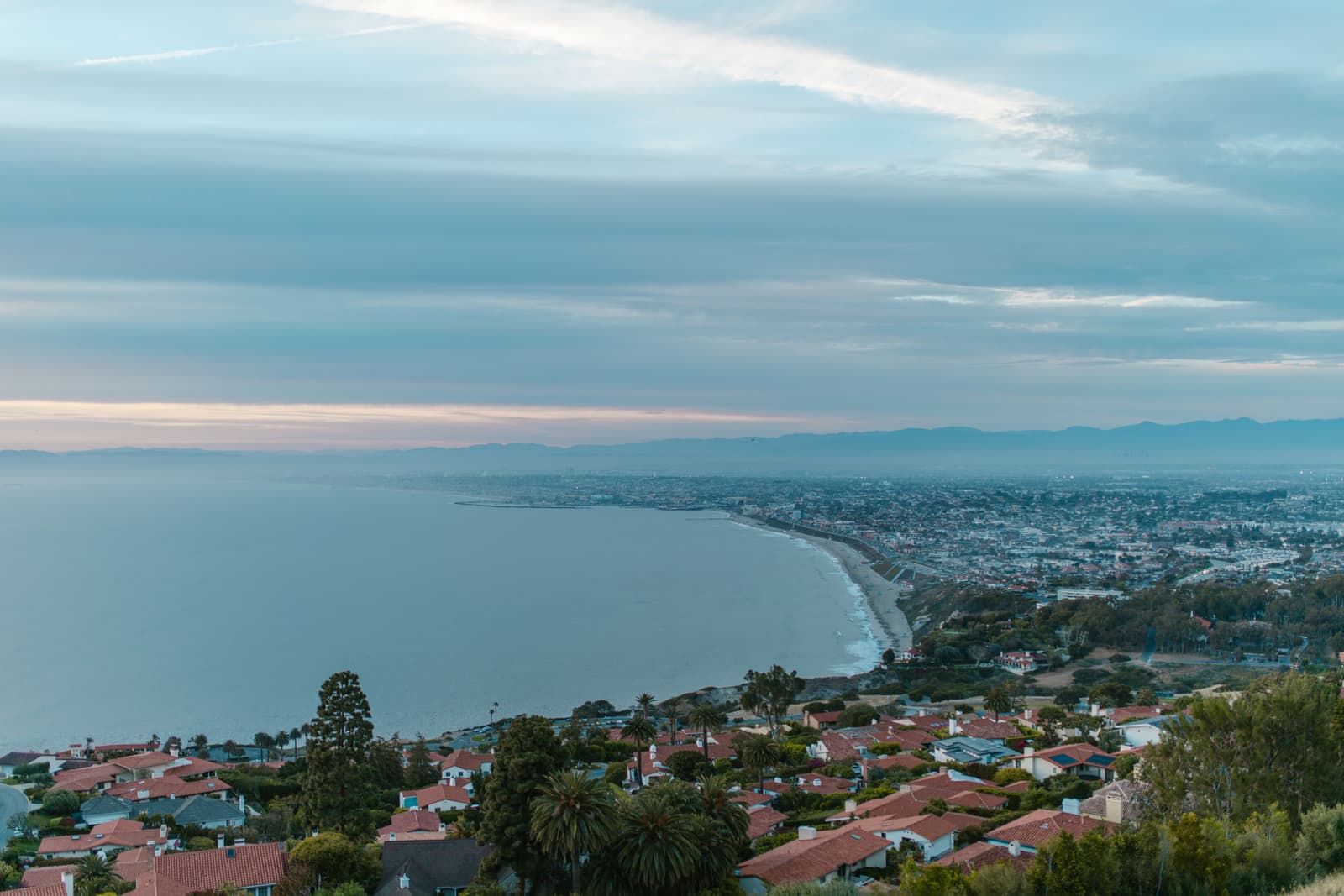 Twilight over Torrance Beach and the South Bay coast from the Palos Verdes hillside, red tile roofs stepping down toward the water