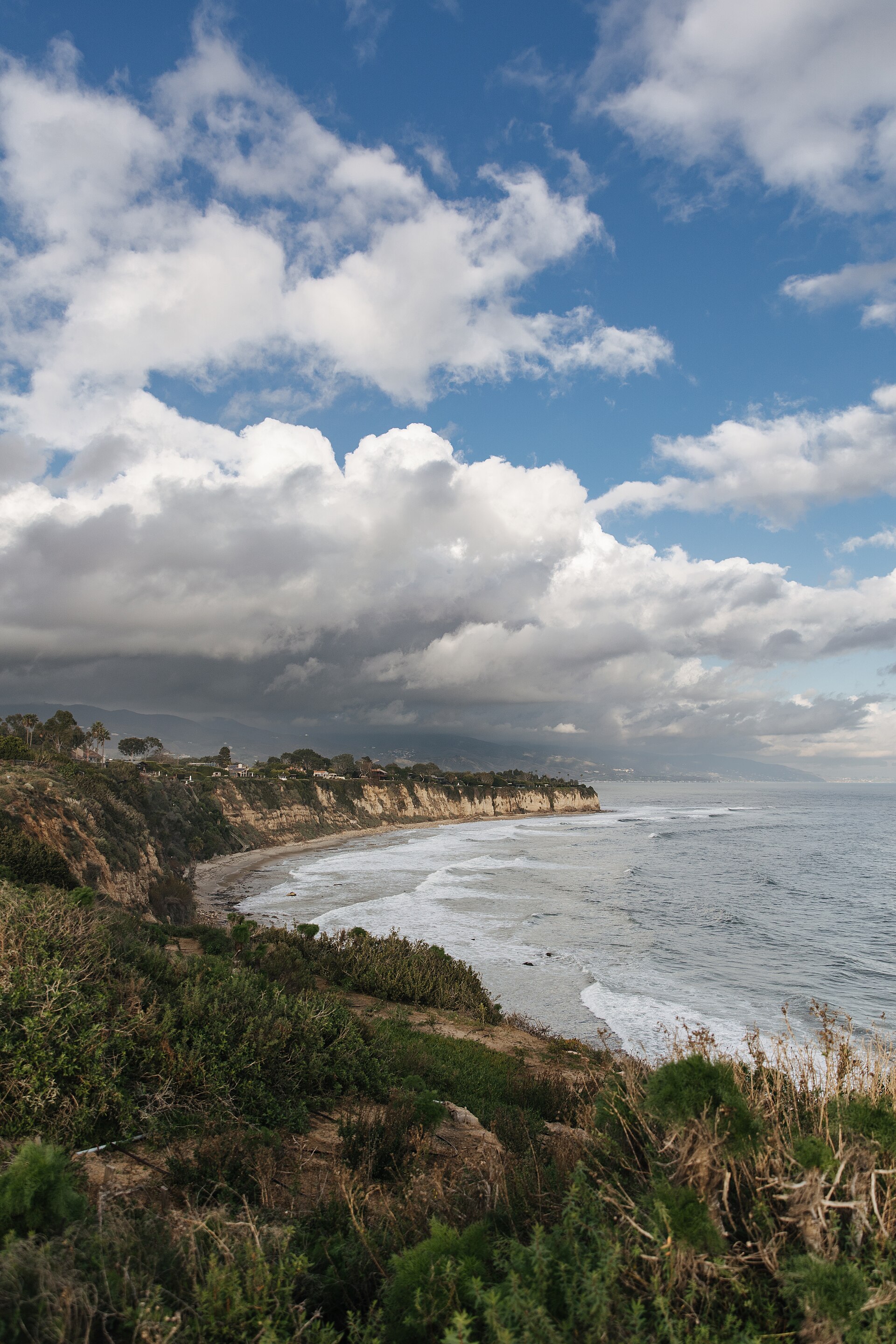 Homes along the Malibu bluffs above a cove, with the coast stretching east